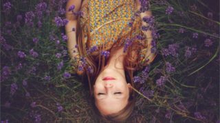 Sleeping woman surrounded by lavender on the grass