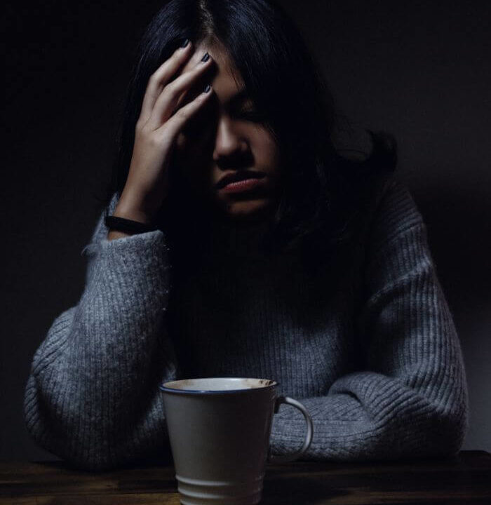Depressed woman in blue clothes with one hand on head