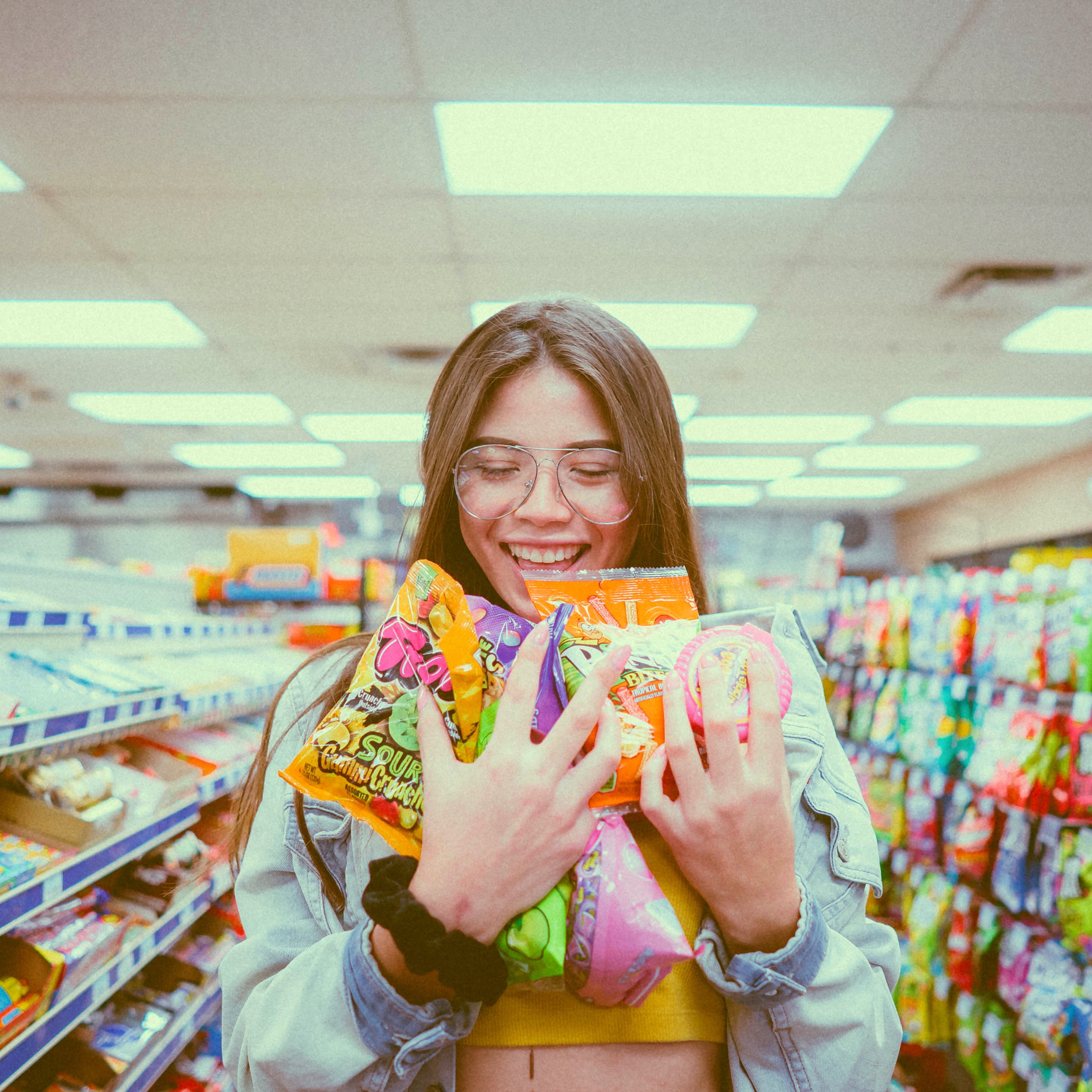 smiling woman holding pack of food inside grocery store