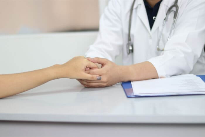 The doctor is holding the patient's hand