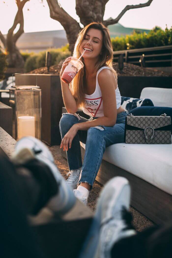 Woman drinking smoothie while sitting on couch outdoors