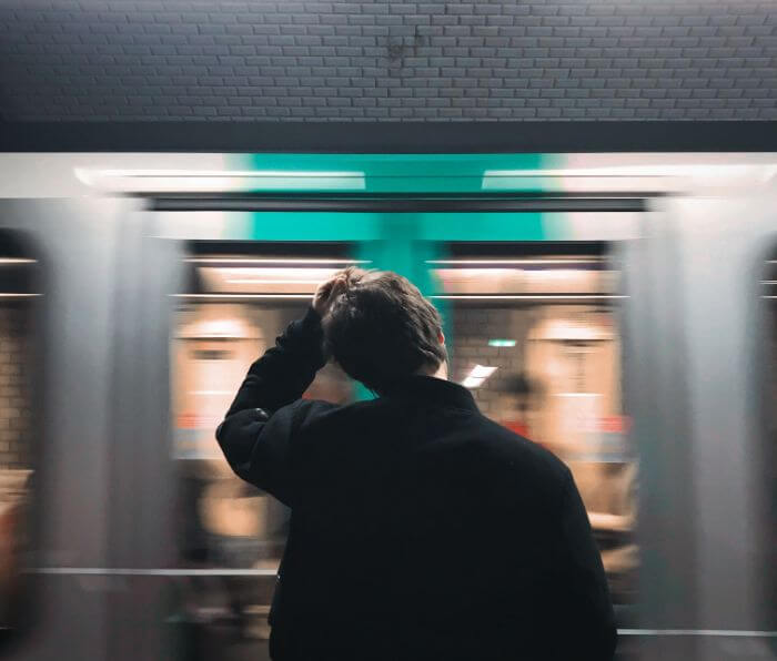 A train passing by in front of a man holding a head