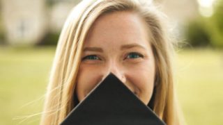 woman covering her face with black mortar board