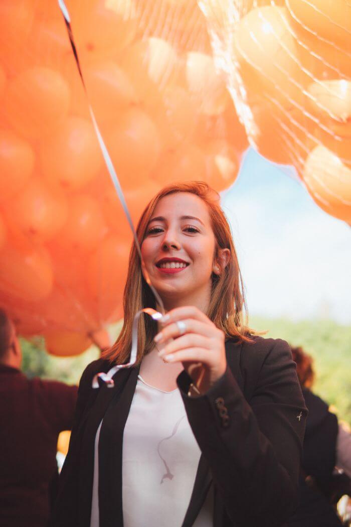 woman standing under orange balloons