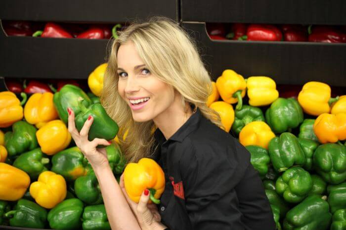 Smiling woman in front of peppers and paprika