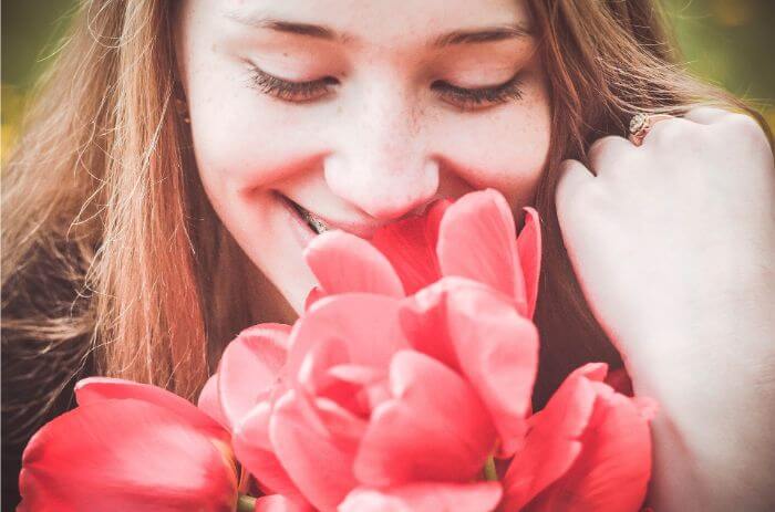 A woman smelling the scent of a red bouquet